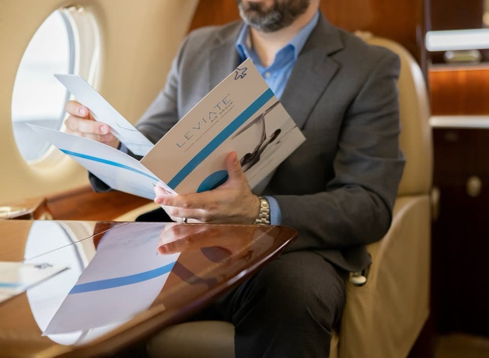 A Leviate broker reviewing aircraft documents in a private jet cabin